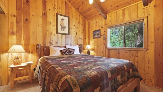 Primary bedroom with a California King size bed, plush bedding, smart TV, and peaceful forest views