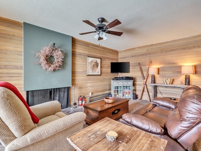 View of the living room equipped with comfortable seating, flat screen tv, ceiling fan and fire place