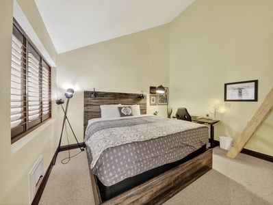 Primary bedroom with a California King bed, desk and chair workstation, and access to loft. Located on the second level