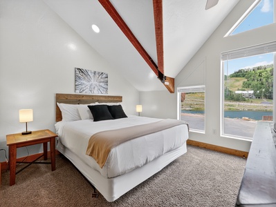 Primary bedroom featuring a king-size bed with plush bedding, smart TV, and serene views of the pond and park