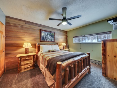 Primary bedroom featuring rustic and unique furnishings, comfortable bedding, a ceiling fan, and a flat-screen TV for a relaxing stay