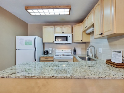 Fully stocked kitchen with stone countertops, a tile backsplash, and all the amenities needed to prepare meals after a day on the slopes