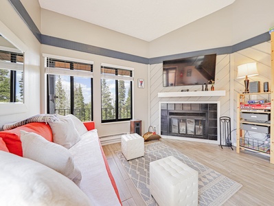 Living room area with sleeper sofa, large windows with views to the trees and 48" smart TV