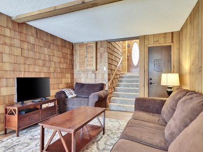 View of the inviting living room featuring comfortable seating, a 38" flat-screen TV, DVD player, and a cozy wood-burning fireplace