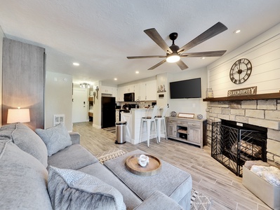 View of Living Room with Wood Burning Fire Place, 65" TV, Sleeper Sofa and Ceiling Fan