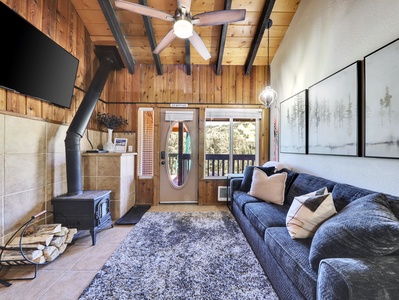 View of Living Room with Wood Burning Fire Place, 65" Smart TV, Ceiling Fan