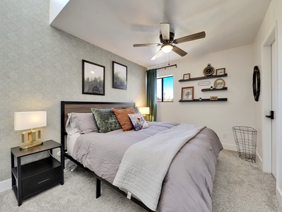 Primary bedroom featuring a king-size bed with plush bedding, modern decor, and a ceiling fan for enhanced comfort