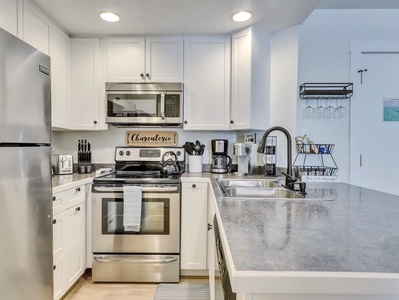 View of the Kitchen Including Microwave, Oven, Stove, Refrigerator, Stainless Steel Sink, Blender, Kettle, Crock Pot, Knife Block