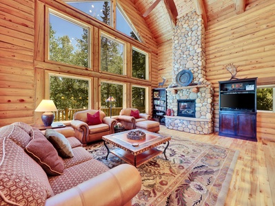 Spacious living room featuring a stunning floor-to-ceiling gas fireplace and expansive forest views
