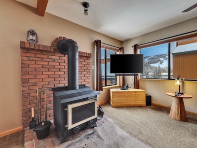 Inviting living room featuring a beautiful rustic wood-burning stove and a 55" smart TV for cozy mountain relaxation