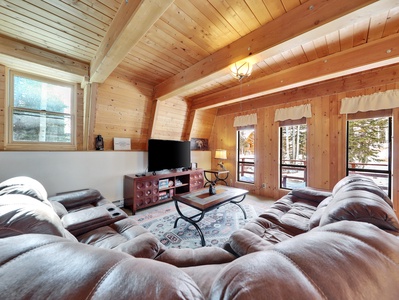 View of the living room, featuring a 55" Smart TV, comfortable couch, and views of the trees