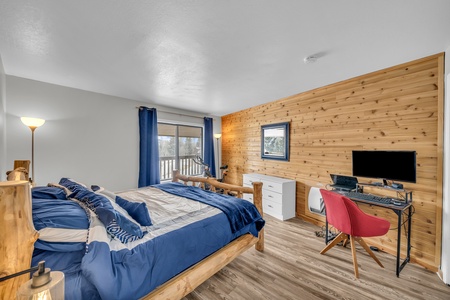 Spacious primary bedroom featuring a king-size bed, dedicated workspace with desk and chair, stunning floor-to-ceiling windows, and direct access to the private balcony