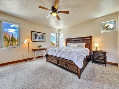 Primary bedroom featuring a king-size bed, ceiling fan, nightstands with lamps, and a spacious walk-in closet