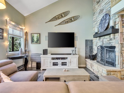 View of Living Room Sofa, smart TV, vaulted ceiling, fireplace, floor lamps, entertainment console, coffee table