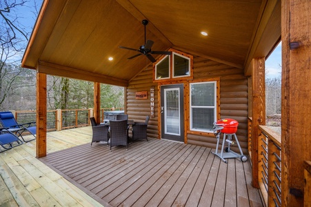 Outdoor dining area with a grill and a ceiling fan.