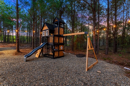 A wooden playscape with slide and swing for children to enjoy.