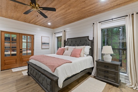 The upstairs king bedroom en suite features an upstairs patio balcony with elevated views of the surrounding forest.