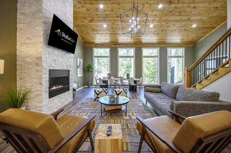 The spacious living room has floor to ceiling windows providing beautiful natural light. Cozy up next to the stunning stone fireplace to enjoy a movie on the smart tv.