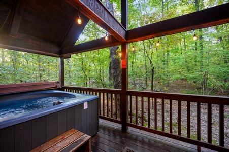 Your private hot tub sits on the wraparound deck with wooded views around you and moody cafe lights above.