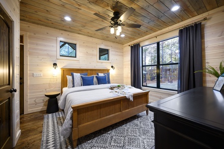 Wake up to peaceful forest views from the master bedroom, featuring a plush king bed and stylish rustic decor for a cozy night's sleep.