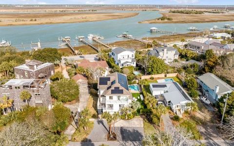 Aerial view of a residential neighborhood with houses near a winding river, docks, and surrounding greenery.