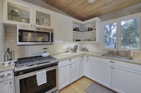 Kitchen corner white cabinets with stainless steel microwave over a stove and over combination.