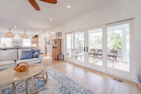 Living room view into the screen porch through four large glass sliding doors. with wood chairs.