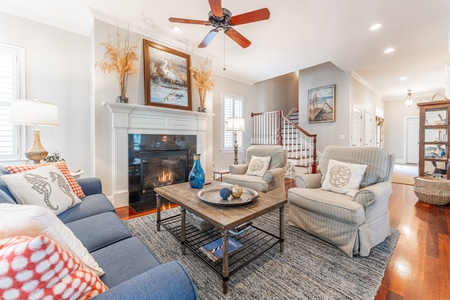 Cozy seating area around fire place. Two chairs, table and sofa. Stairs in the back ground right to left.