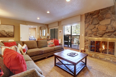 Cozy living room area featuring a fireplace, large TV, access to balcony.