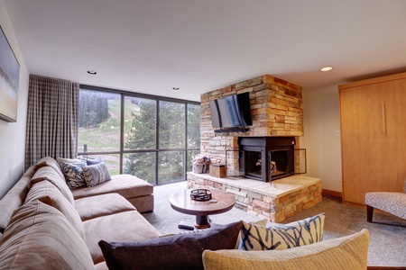 Living room space with large floor to ceiling windows and a cozy fireplace.