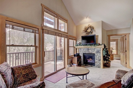 Open concept living room features private balcony access, fireplace, and TV.