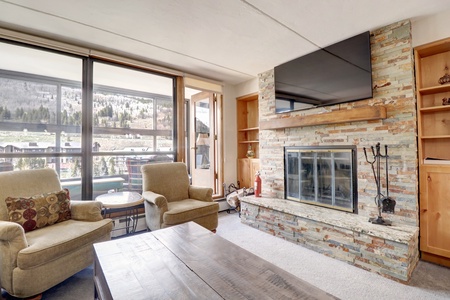 Large TV with wood burning fireplace, access to an enclosed porch.