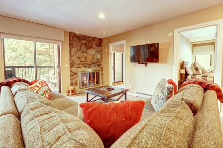 Cozy living room area with fireplace, large TV, and views out onto the patio.