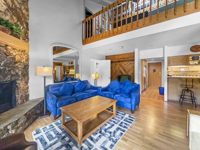 Open concept living room with cozy seating, a fireplace, and loft shown above.