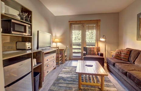 Cozy seating area with large TV, mini fridge, microwave, and coffee maker.