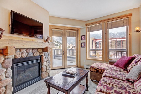 Living room features a fireplace and access to a private balcony with mountain views.