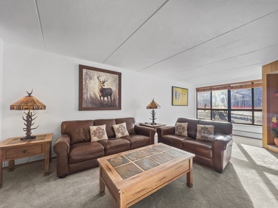 Large living room with bright windows looking out to the American Eagle chairlift and magic carpet area.