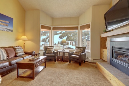 Bright open concept living room with large windows offering views of the ski slopes.