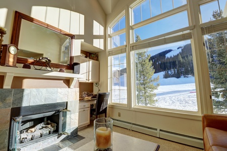 The cozy living room offers a fireplace and large picturesque windows.