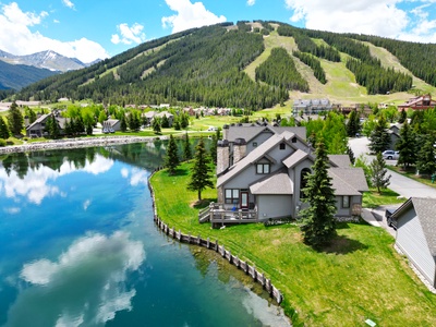 Beautiful aerial view of townhouse with pond in the back and Copper Mountain ski slopes in background.