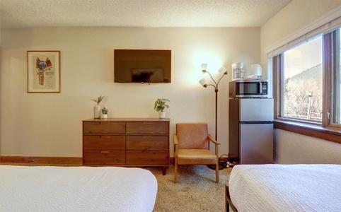 The hotel room features a TV, seating area, coffee maker, microwave, and fridge.