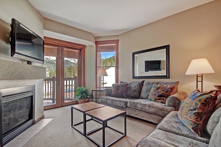 The cozy living room offers access to a private patio, fireplace, and large TV.