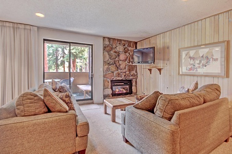 Cozy living room offers a fireplace, TV, and private balcony.