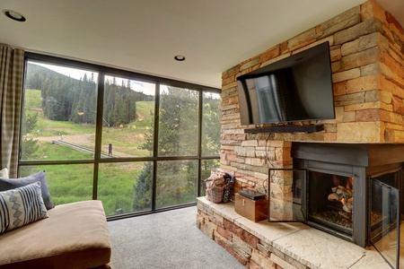 Living room space with large floor to ceiling windows and a cozy fireplace.