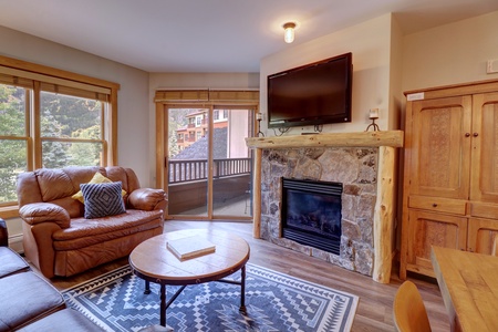 Cozy living room with fireplace and TV, access to private balcony.