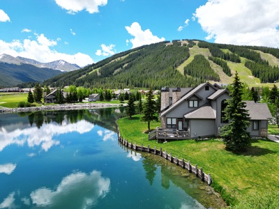 Beautiful aerial view of townhouse with pond in the back and Copper Mountain ski slopes in background.