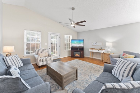 Spacious, sunlit living room with comfy seating, smart TV, and an electric fireplace—ideal for family time or a cozy night in.