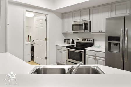 Modern kitchen with stainless steel appliances and cookware.