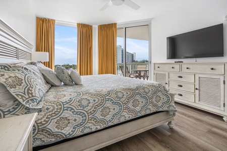 Primary bedroom with balcony access and flatscreen television.