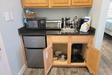 Kitchenette with a microwave, small refrigerator and sink.